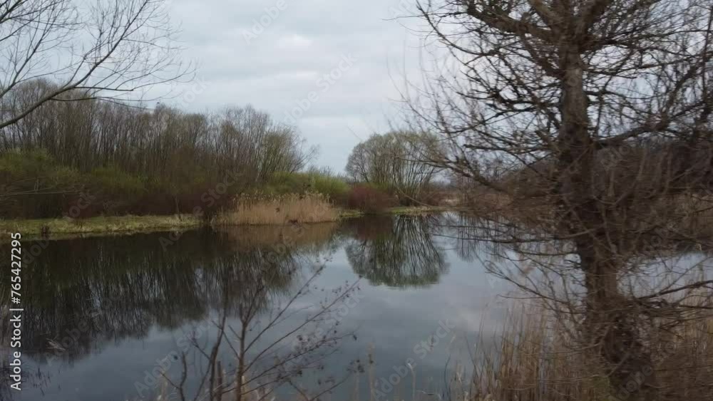 Jesienny dzień nad jeziorem z odbijającym się niebem w tafli wody Jesienny dzień nad jeziorem z odbijającym się niebem w tafli wody