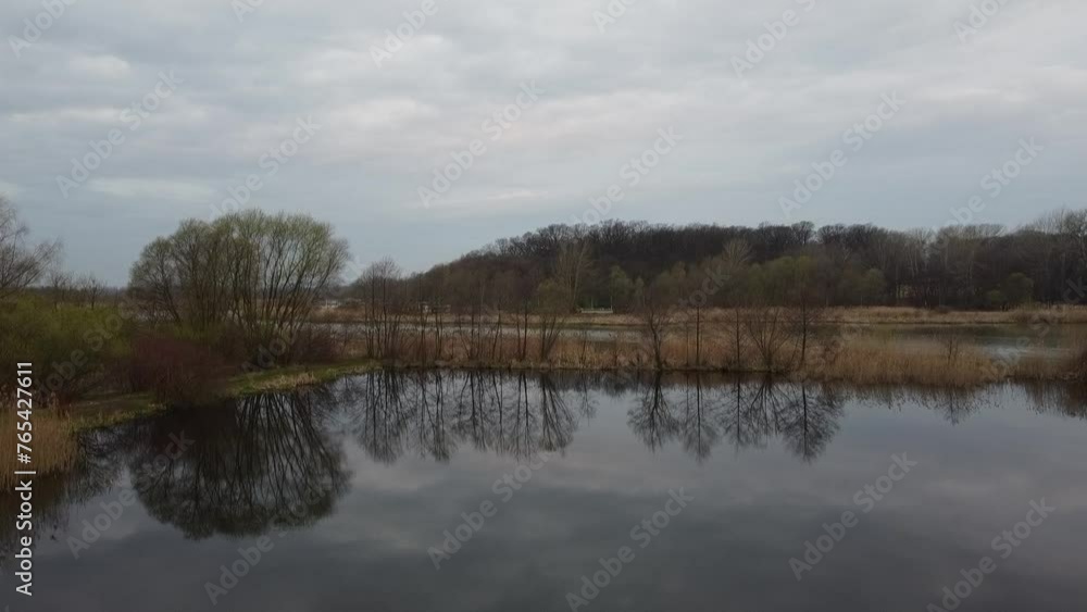 Jesienny dzień nad jeziorem z odbijającym się niebem w tafli wody Jesienny dzień nad jeziorem z odbijającym się niebem w tafli wody