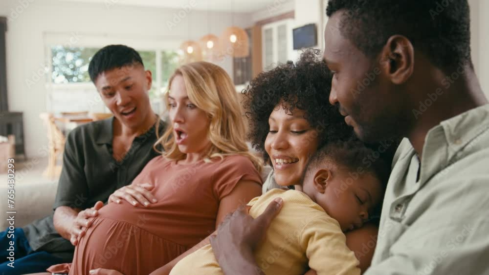 Pregnant couple visiting new family with sleeping baby daughter cuddling her sitting on sofa at home - shot in slow motion Pregnant couple visiting new family with sleeping baby daughter cuddling her sitting on sofa at home - shot in slow motion