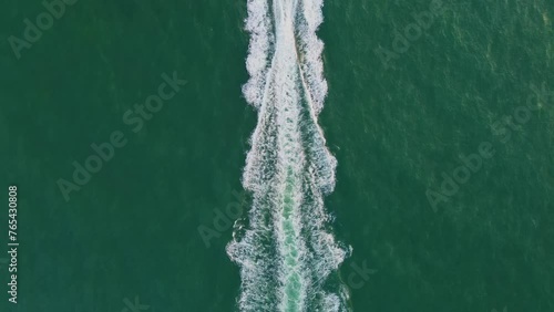 The white water trail of a speedboat running on the sea was filmed from the air by a drone.