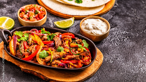FAJITAS with colored pepper and onions, served with tortillas.