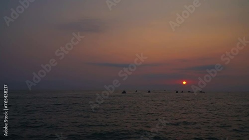 Time lapse of sea landscape at dawn with silhouettes of boats passing by.
