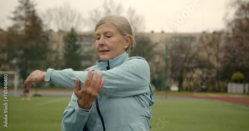 Aged woman doing exercises in public stadium