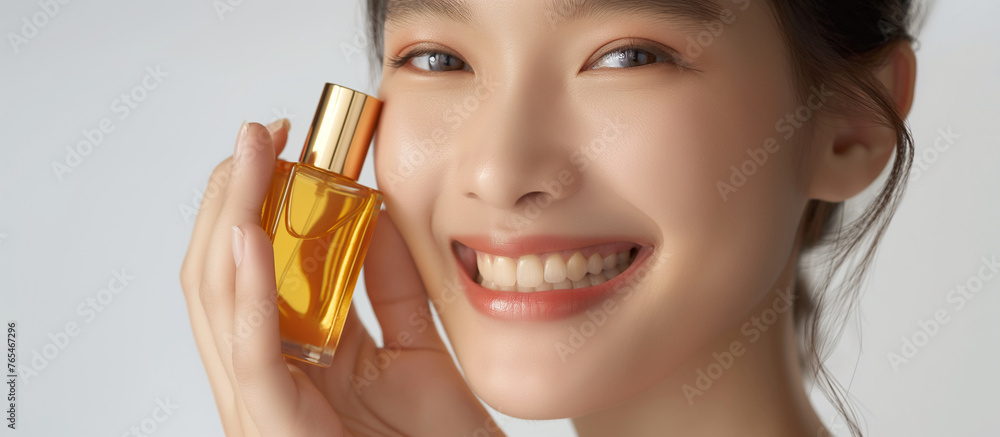 Fototapeta premium A woman is holding a bottle of perfume and smiling