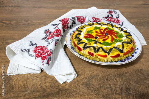 Traditional Romanian boeuf (beef) salad decorated for Christmas or Easter with a traditional towel on a wooden table