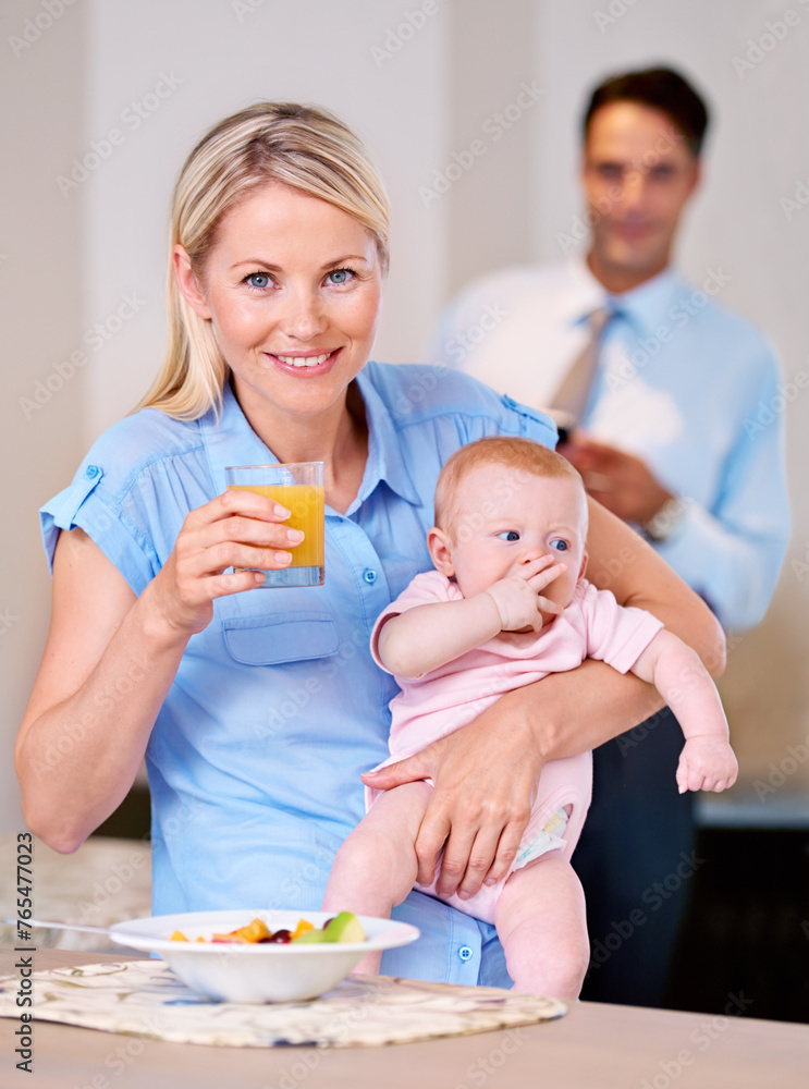 Portrait, mother and baby with juice and breakfast in the morning with businessman leaving for work. Woman, food and eating fruit with little child or kid for healthy diet and father in background Portrait, mother and baby with juice and breakfast in the morning with businessman leaving for work. Woman, food and eating fruit with little child or kid for healthy diet and father in background