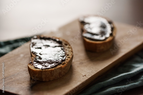 Rustic bread slices with chocolate spread on olive wood board closeup