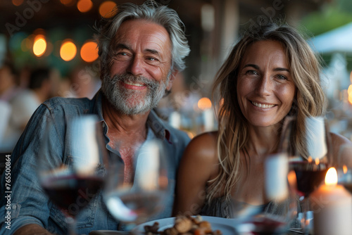 A mature couple celebrates at a restaurant with friends  enjoying wine and laughter.