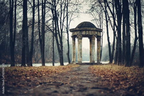 The old rotunda in the park in autumn. Silhouettes of naked black trees without leaves during the fall season. Melancholic landscape photo