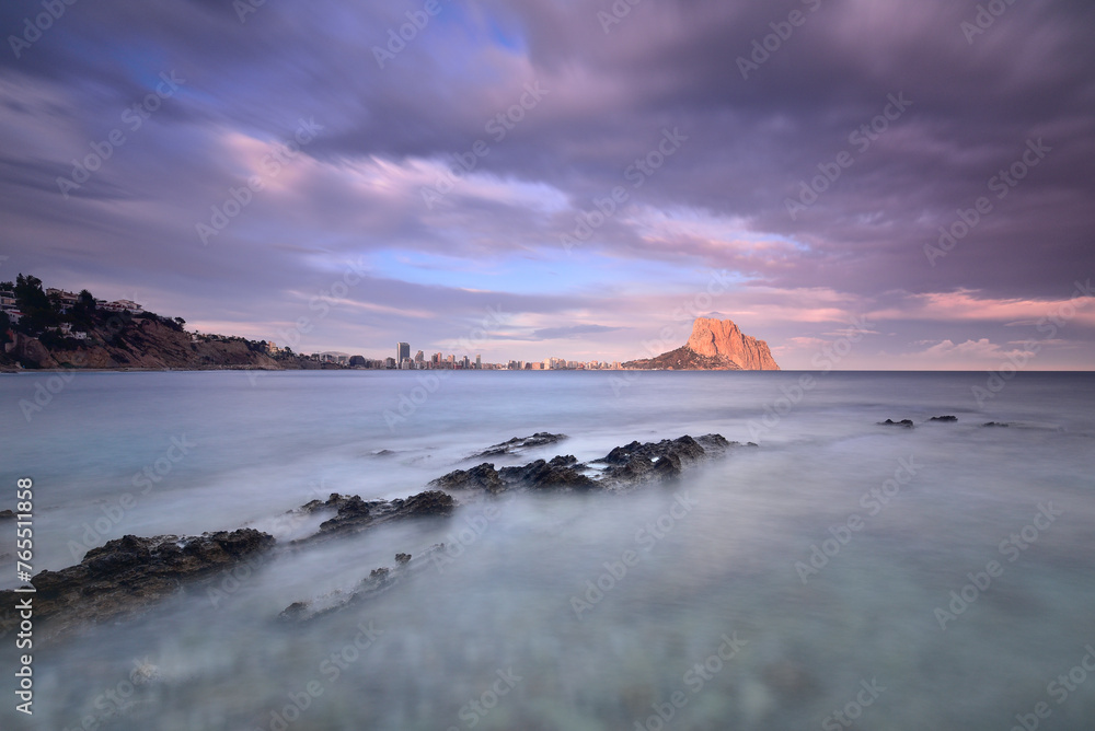 Coastal landscape with the Peñon de Ifach on the horizon at sunset.