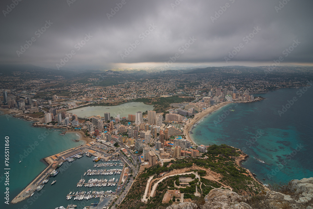 Aerial view of the city of Calpe. The sky is cloudy and the city. You can see the fishing port.