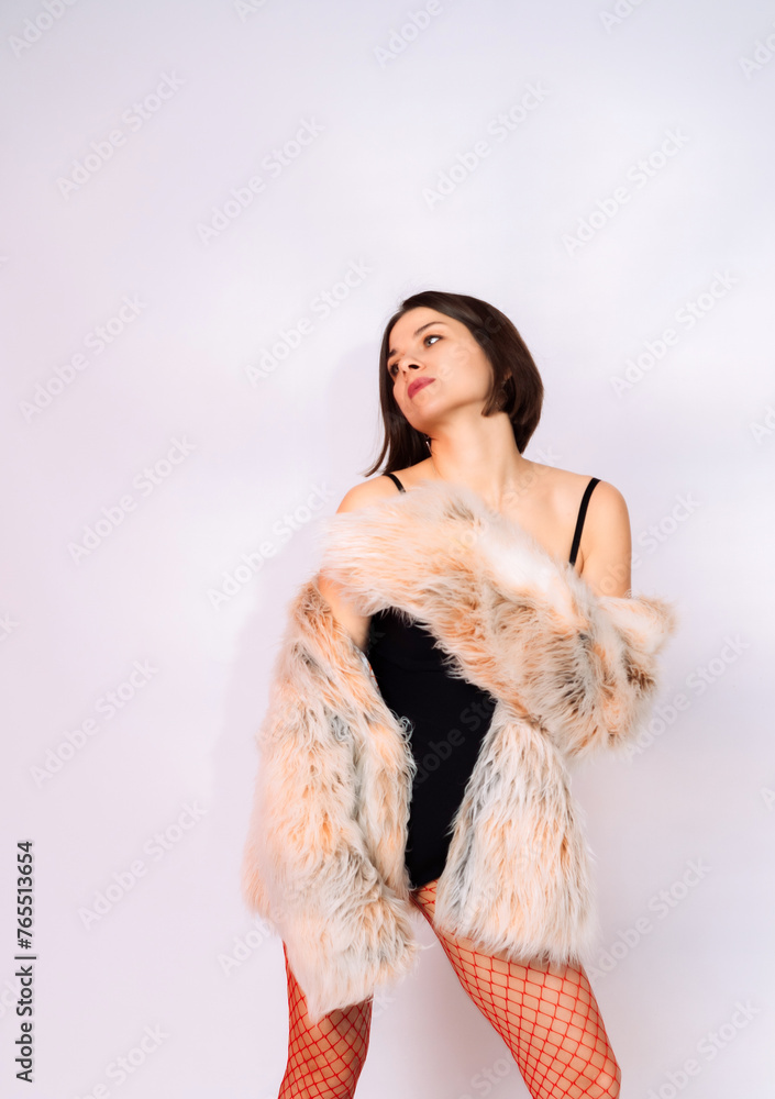 Girl in a fur coat and red shoes in the studio with flowers Girl in a fur coat and red shoes in the studio with flowers