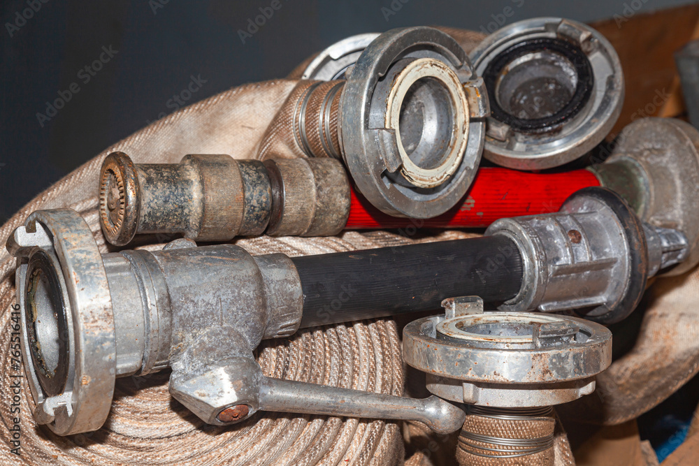 Twisted old fire hoses with connections and nozzles.