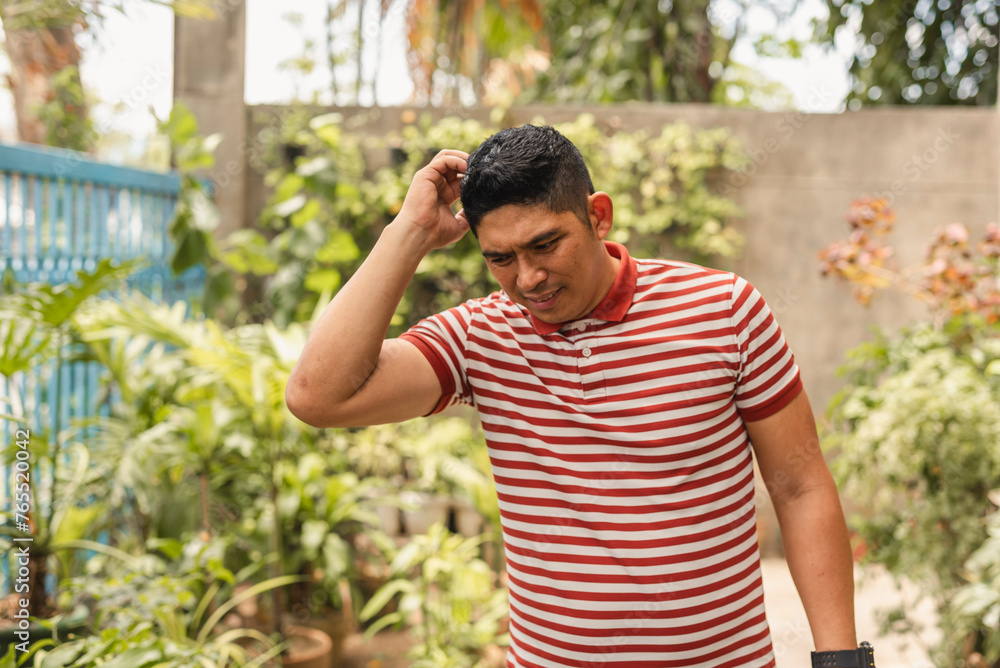 Forgetful Asian man scratching his head in confusion outdoors Forgetful Asian man scratching his head in confusion outdoors