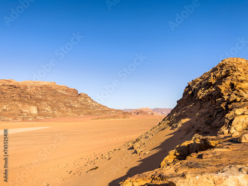 Rocky Canyon and Orange sandy desert under the blue sky in a hot day