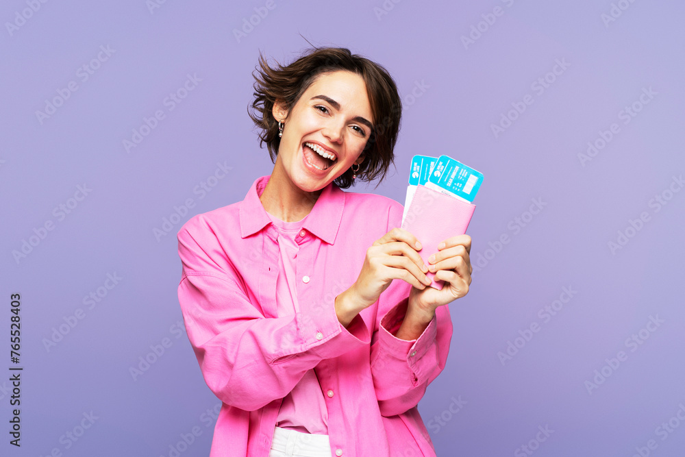 Smiling, attractive woman in pink, with brunette hair, holding travel tickets and documents Smiling, attractive woman in pink, with brunette hair, holding travel tickets and documents