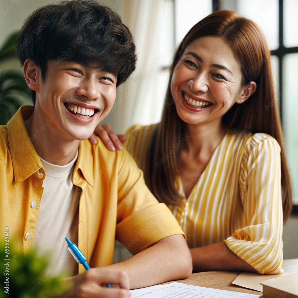 mother and son are sitting at the table, the son writes in a notebook, they laugh mother and son are sitting at the table, the son writes in a notebook, they laugh