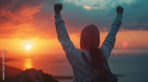Young Woman Celebrating Success at Sunset with Raised Arm