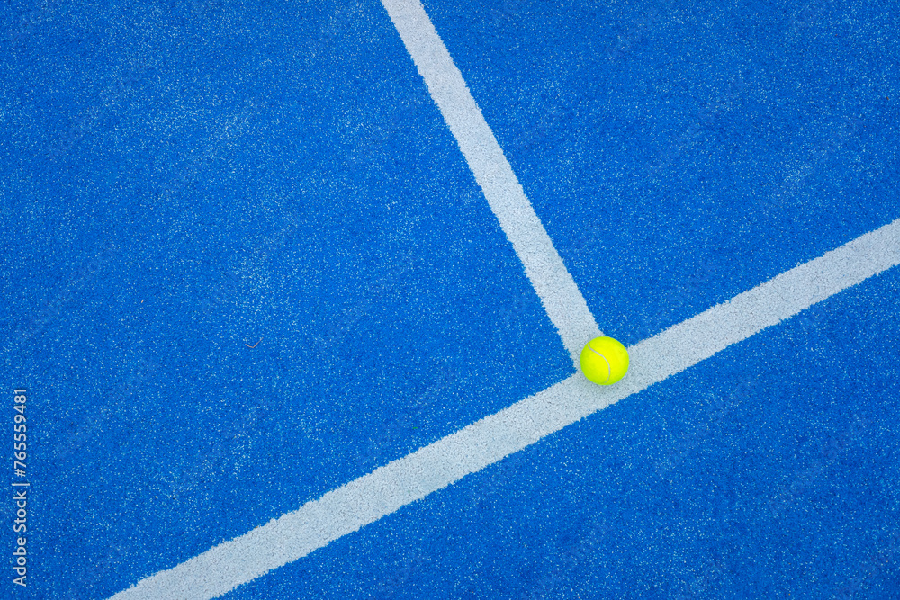 ball on the background line of a blue paddle tennis court