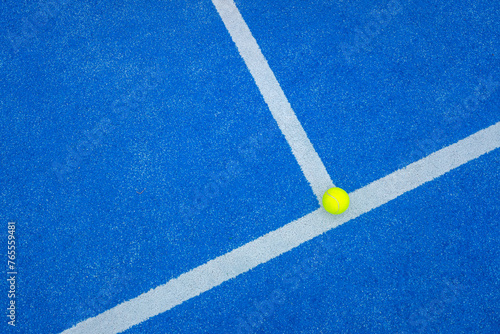 ball on the background line of a blue paddle tennis court © Vic