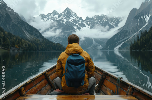 A person sitting in the front of an old wooden boat on Lake passes through mountain lakes, forests and snowy mountains