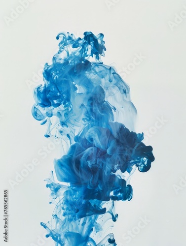 Blue ink disperses and swirls in water against a clean white backdrop, creating intricate patterns and textures