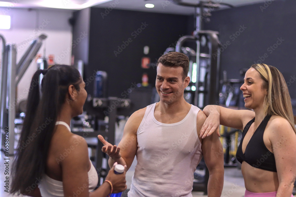 Group of multiracial smiling people talking to each other inside a gym, sport dressed. Fitness concept with normal people Group of multiracial smiling people talking to each other inside a gym, sport dressed. Fitness concept with normal people