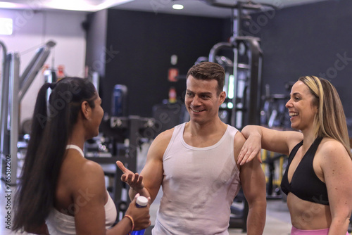 Group of multiracial smiling people talking to each other inside a gym, sport dressed. Fitness concept with normal people