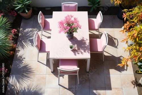 an elegant outdoor dining area featuring a gas barbecue, a well set dining table, and beautiful flowers on a paved patio, captured from a bird s eye view.