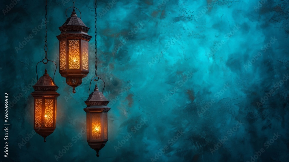 Three elegant lanterns hanging gracefully in front of a vibrant blue background against a dark setting