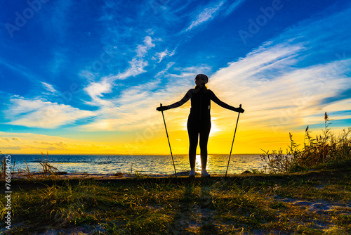 Nordic walking - beautiful woman exercising by the sea
