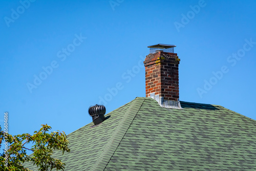 Brick chimney and metal vent on a house shingled roof in Boston, USA