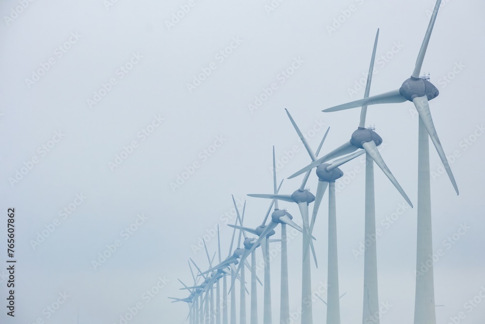 Fototapeta premium wind turbines in a row on the coast in the mist and fog
