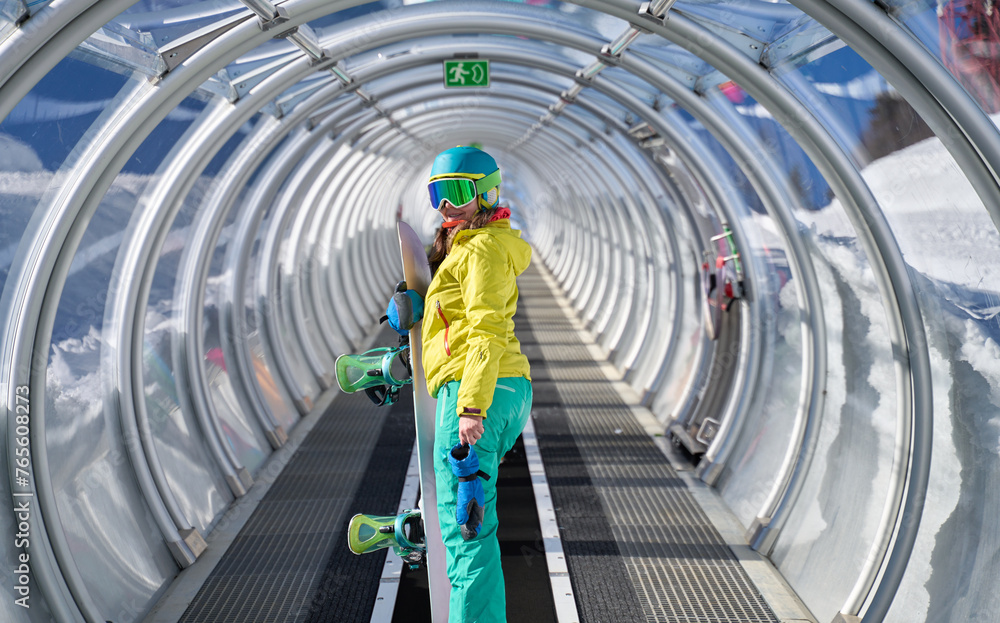 Snowboarder on Covered Escalator to Slopes