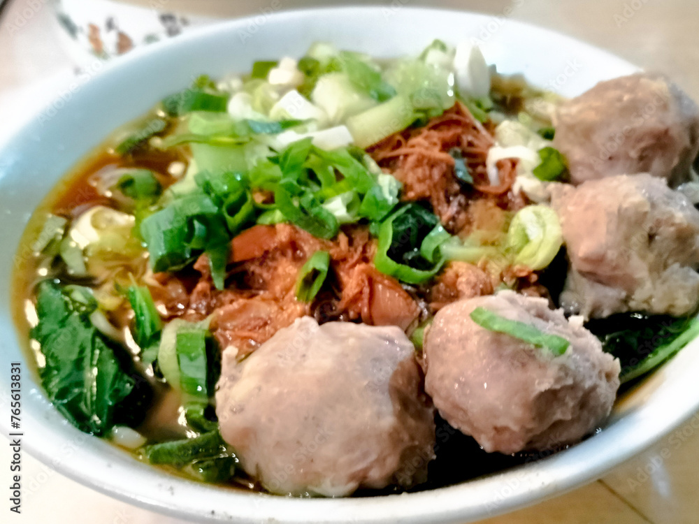 A bowl of traditional noodle called Mie Ayam Bakso taken from top angle. Top angle of Mie Ayam Bakso on a white bowl with meatball. A bowl of traditional noodle called Mie Ayam Bakso taken from top angle. Top angle of Mie Ayam Bakso on a white bowl with meatball.