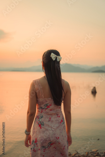Asian woman in dress with calm mood on the lakeside in the sunset