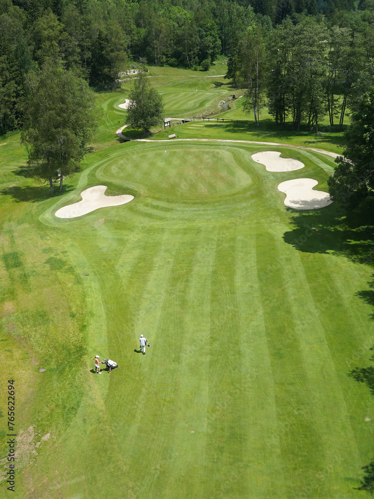 Luxurious beautiful golf course with well prepared green, fairway and bunkers and couple of golfers, panoramic view, Chamonix, France
