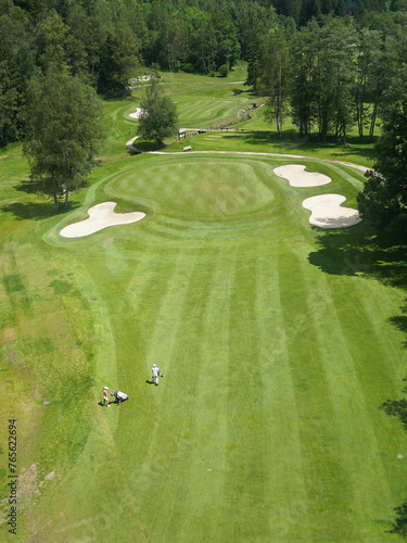Obraz na płótnie Luxurious beautiful golf course with well prepared green, fairway and bunkers and couple of golfers, panoramic view, Chamonix, France w salonie