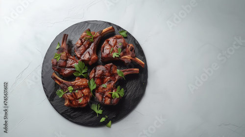 Grilled lamb chops on a slate platter, top view, on a light grey background