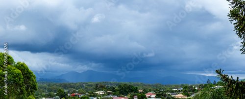 Rain and storm clouds over suburbia and mountain range photo