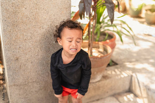 Upset Asian toddler boy crying during a tantrum outdoors photo