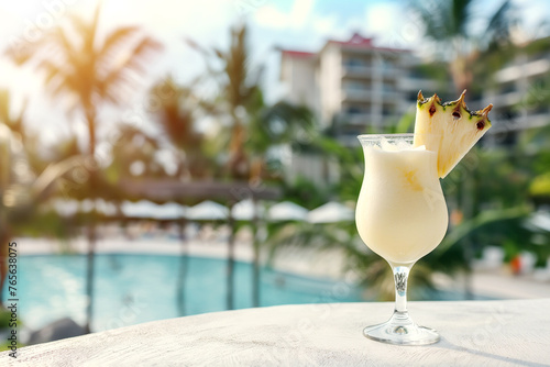 Pina colada cocktail in a glass on a white concrete surface against the background of a luxury tropical hotel photo