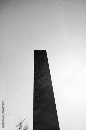 A tall stone obelish tower standing against the sky in black and white. photo