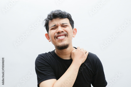 Wallpaper Mural an asian man holds his shoulder and looks in pain Torontodigital.ca