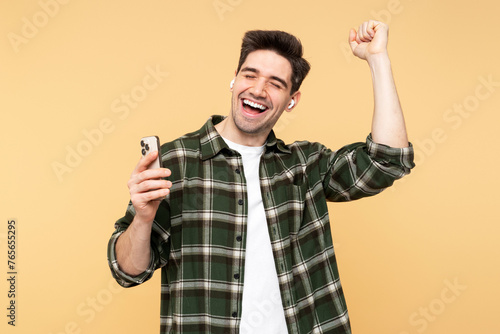 Smiling man holding his mobile, dancing, and singing into earbuds, enjoying music, eyes closed