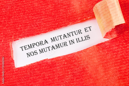 Tempora mutantur et nos mutamur in illis Translated from Latin, it means Times are changing, and we are changing with them. on a white background under torn paper photo