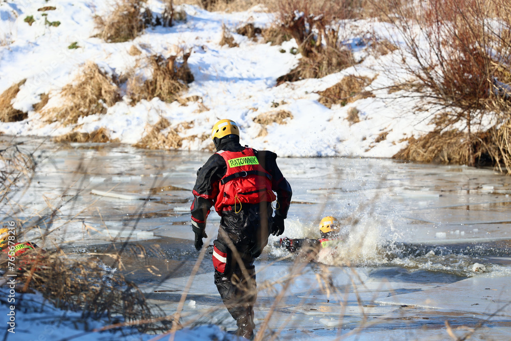 Ratownik wodny w zimie na lodzie ratuje topielca. 