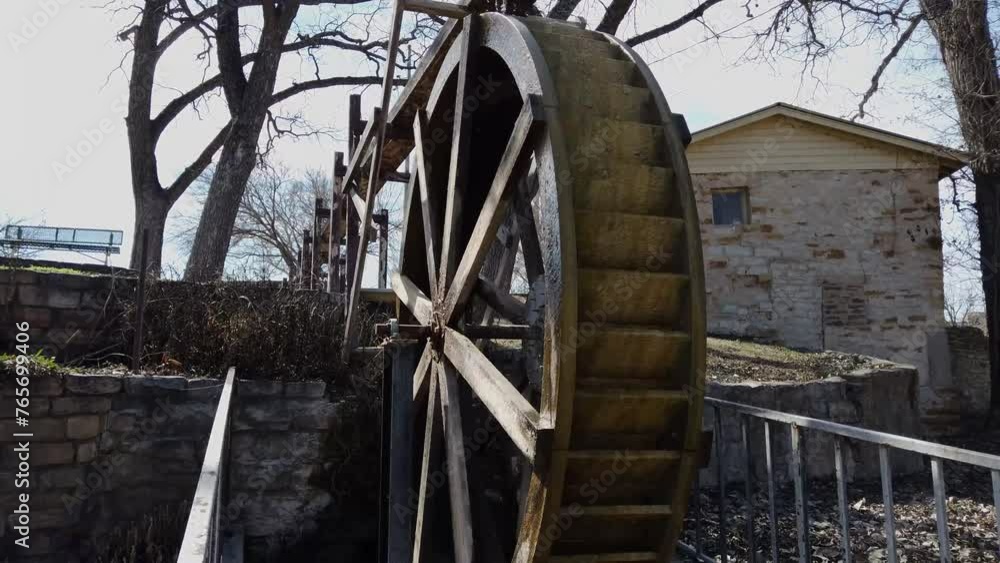 Waterwheel turns with stone building in background Waterwheel turns with stone building in background