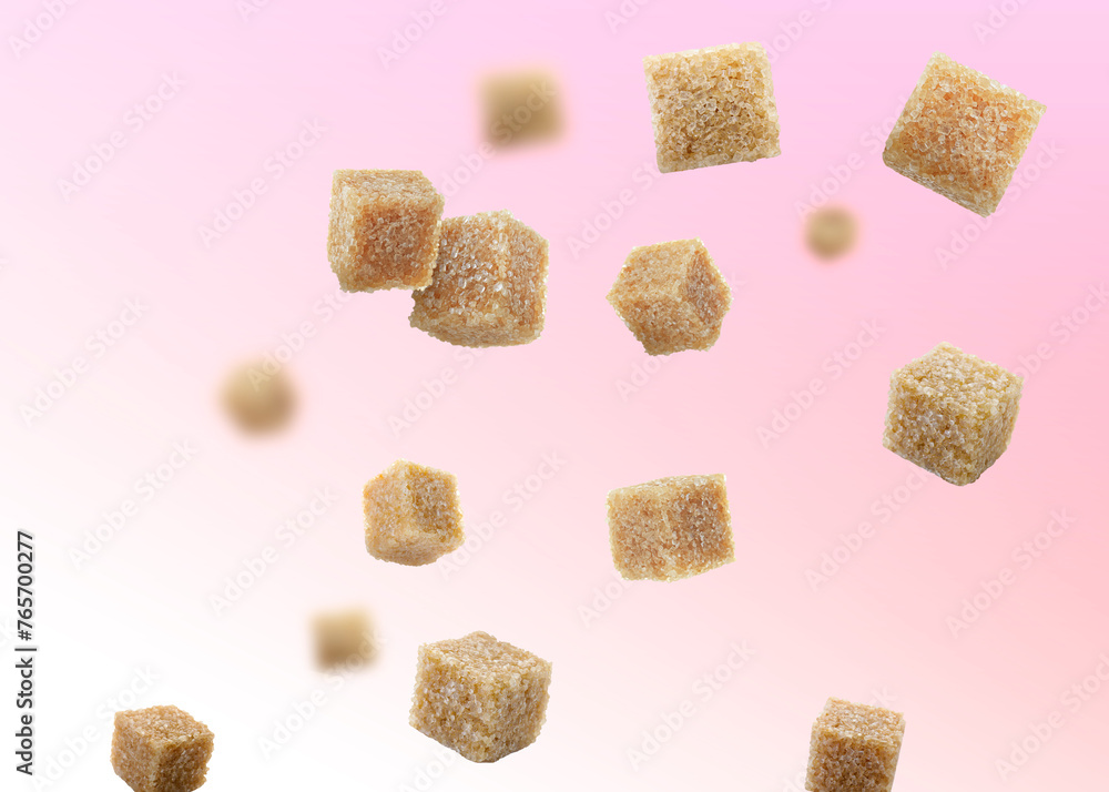 Brown cane sugar cubes falling on color gradient background Brown cane sugar cubes falling on color gradient background