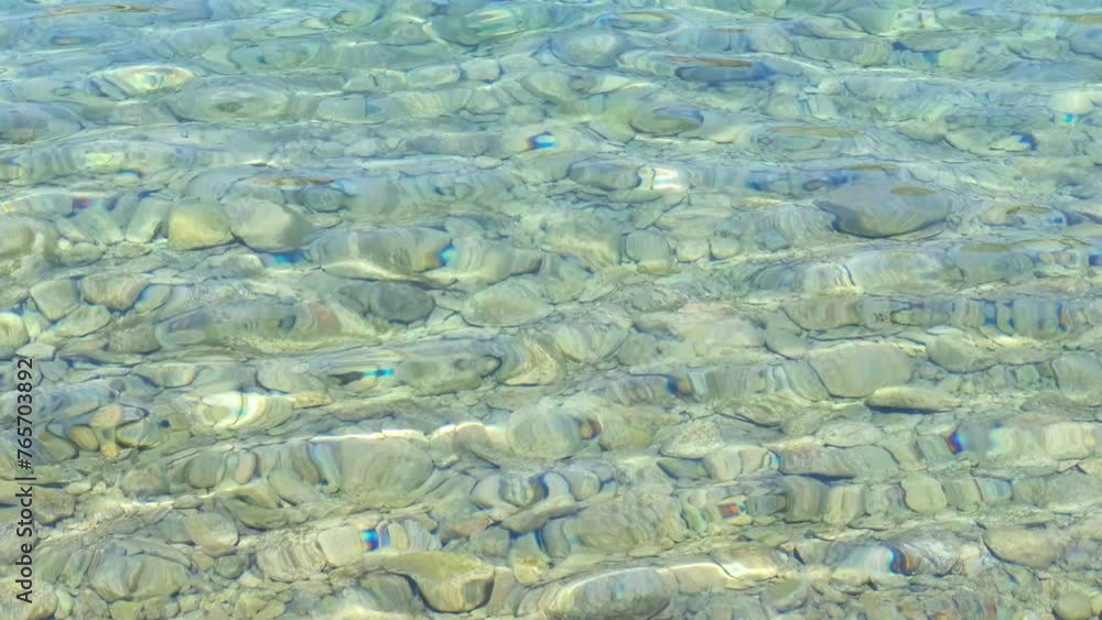 Crystal clear and transparent turquoise sea water washes over the pebbles on the seabed. The water glistens and shimmers in the sun. Concept of travel, summer seaside holiday. Copy space. Crystal clear and transparent turquoise sea water washes over the pebbles on the seabed. The water glistens and shimmers in the sun. Concept of travel, summer seaside holiday. Copy space.